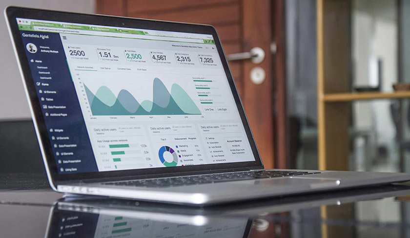 Laptop cu grafice de analiză a performanței și tabletă cu calendar, utilizate pentru planificare și raportare în project management